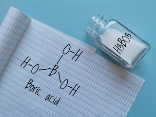Structural chemical formula of boric acid molecule (hydrogen borate or orthoboric acid) with white crystalline boric acid in a glass jar. It is used as an antiseptic, insecticide, flame retardant, etc