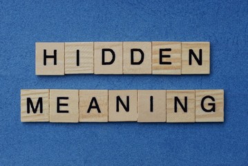 Fototapeta premium phrase hidden meaning in small square wooden letters with black font on a blue background