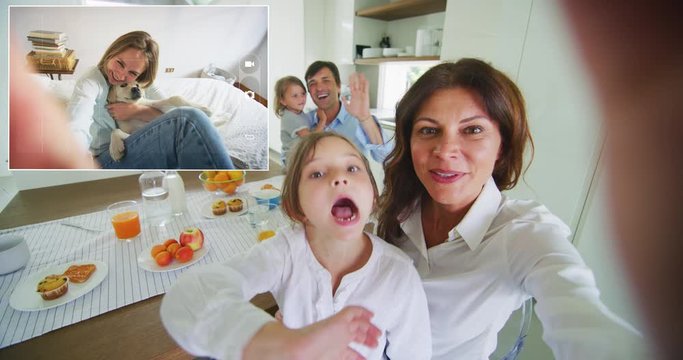 A happy smiling family is making technology video call with to their bigger daughter while having a breakfast together in a kitchen at home in the morning.	