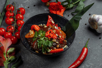 Beef wok. Traditional chinese mongolian beef stir fry in chinese cast iron wok with cooking chopsticks, stone slate background. Top view, copy space