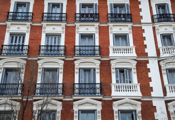 Urban architecture and design. Closeup view of an apartment brick wall facade, windows and french balconies.