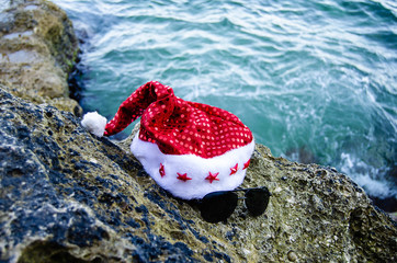Happy New Year holidays and Merry Christmas at Sea. christmas hat lying on the rocks