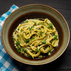 Creamy green pasta with poblano pepper and parmesan cheese on dark background