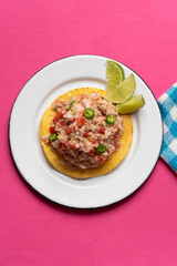 Canned tuna ceviche with chili pepper and tomato on pink background