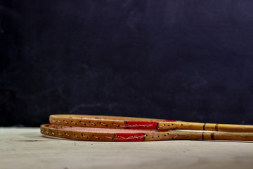 Vintage badminton racket on a black background. Badminton racket on plywood. Racket and shuttlecock on a textured black background. Vintage sport rackets with shuttlecock.