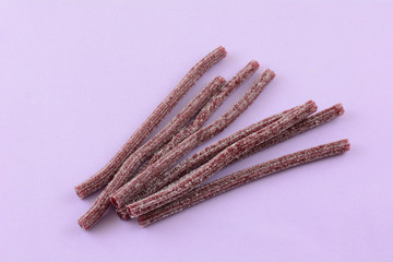 Sour blueberry fruit flavored gummy candy sticks on lavender background