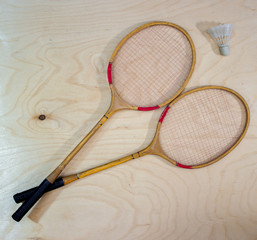 Vintage badminton racket on a wooden background. Badminton racket on plywood. Racket and shuttlecock.