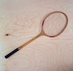 Vintage badminton racket on a wooden background. Badminton racket on plywood. Racket and shuttlecock.