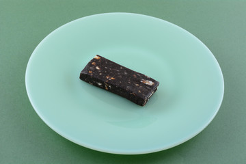 Mint chip fruit and nut snack bar on green plate on green background