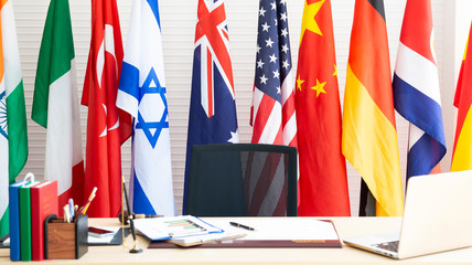 Empty room for president or government statesman with laptop, year planner, business charts and diagram, pen on wooden table and various international flag. Country Leader Room with flags. Press room.