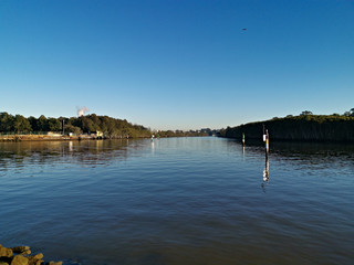 Beautiful view of a river with reflections of deep blue sky and trees on water, Parramatta river, Wilson Park, Silverwater, Sydney, New South Wales, Australia
