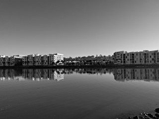 Beautiful black and white view of a river with reflections of modern apartment buildings, clear sky and trees on water, Parramatta river, Wilson Park, Silverwater, Sydney, New South Wales, Australia
