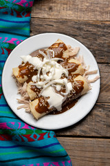 Mexican chicken enchiladas with mole sauce on wooden background