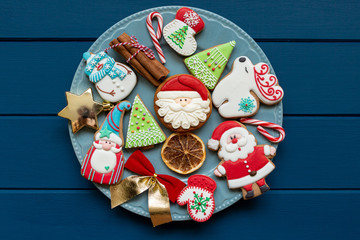 Homemade christmas gingerbread cookies on plate on classic blue wooden background. Snowflake, star, tree, snowman, deer shapes. Holiday, celebration and cooking concept. Close up.