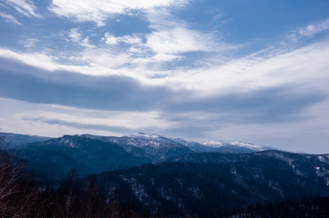 Beautiful winter landscape. Mountain and forest covered with snow, background blue sky.