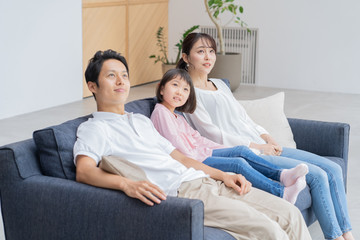 Obraz premium ソファでくつろぐ親子三人 アジア人
