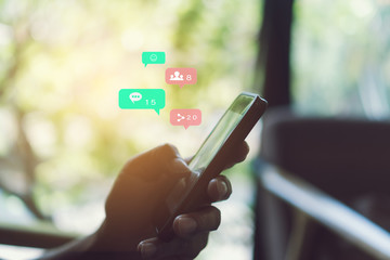 Hand typing keyboard with smartphone with social media and marketing virtual icons screen.