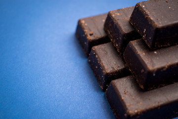 Fresh and sweet chocolate bars on a blue surface 