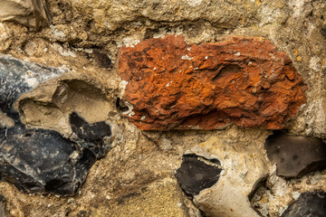 Close up of textured wall surface of ancient ruins. Old English flint stone and hand made red brick weathered by the centuries