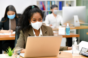 Portrait of Asian woman office worker wearing face mask working in new normal office and doing...
