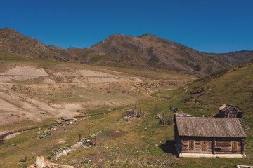 Fototapeta na wymiar Aerial view on old abandoned wooden house in beautiful mountains valley, summer landscape