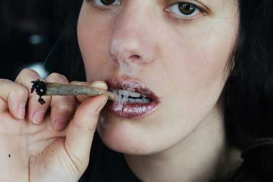 Female lips smoking self-roll weed cigarette. Close-up, lips and fume