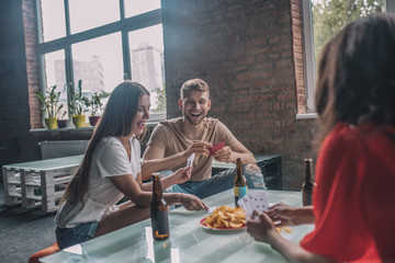 Interested and amused friends playing games with cards