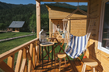 Porch terrace in wooden rustic house with hanging chair, table and chairs