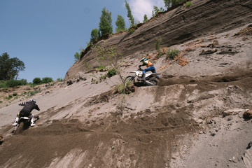 Riders climbing sand mountain on  off-road cross motorcycle