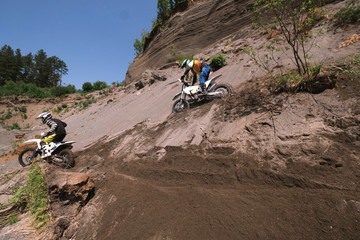Riders climbing sand mountain on  off-road cross motorcycle