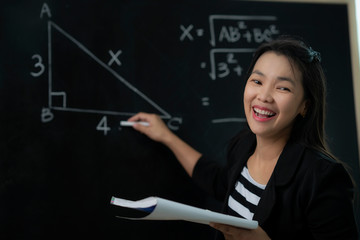 Asian teacher explane mathematics formula to her student in classroom