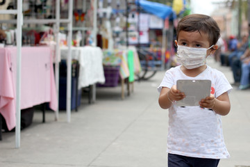 2-year-old Latina girl with protective face masks walking in the square, new normal covid-19