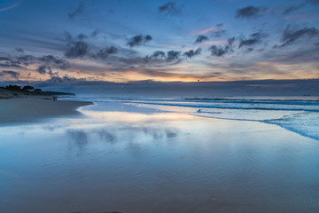 Sunrise seascape with cloud reflections on the beach
