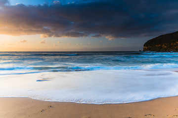 Sunrise at the beach with waves and clouds