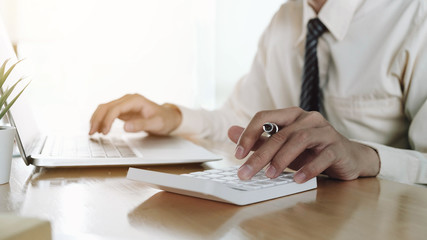 Close up Business woman using calculator and laptop for do math finance on wooden desk in office and business working background, tax, accounting, statistics and analytic research concept