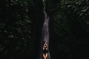 Young and beautiful girl taking bath in a waterfall