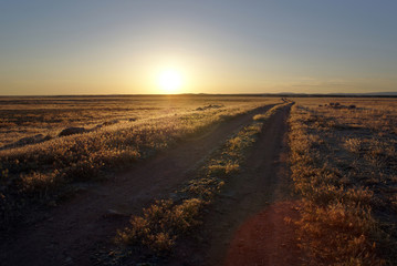 A desert road runs out to the west deserts of Utah and toward Nevada as the sun sets.