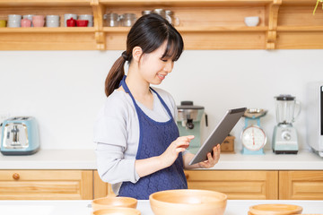 キッチンでタブレットを使う若い女性