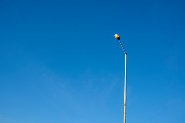 switched on street light against a clear blue sky