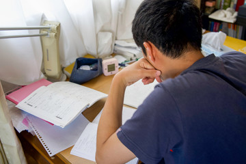 肘をついて勉強する男の子の後ろ姿