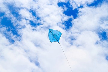 A blue kite flying against a blue sky. Kite flying in the sky among the clouds. Chandpur, Bangladesh / 2020.