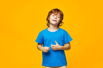 Red-haired boy holding his hands near himself smile childhood studio shot blue t-shirt 