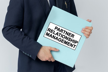 A businessman holds a folder with documents, the text on the folder is - PARTNER RELATIONSHIP MANAGEMENT