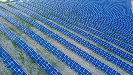 Background of solar panels array as seen from above the modern static solar power station. Green...