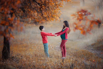 Pregnant woman with boy in the autumn forest. Mother and son. Autumn family portrait. Pregnancy, maternity, expectation concept. Beautiful tender mood photo of pregnancy.