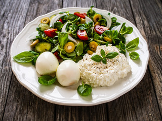 Delicious breakfast - boiled eggs with cottage cheese and vegetables served on wooden table
