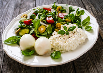 Delicious breakfast - boiled eggs with cottage cheese and vegetables served on wooden table
