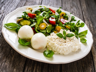 Delicious breakfast - boiled eggs with cottage cheese and vegetables served on wooden table
