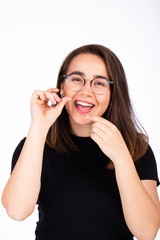 Young beautiful woman in glasses using dental floss on white background