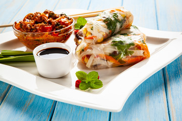 Chinese spring rolls, rice and sauces on wooden table
